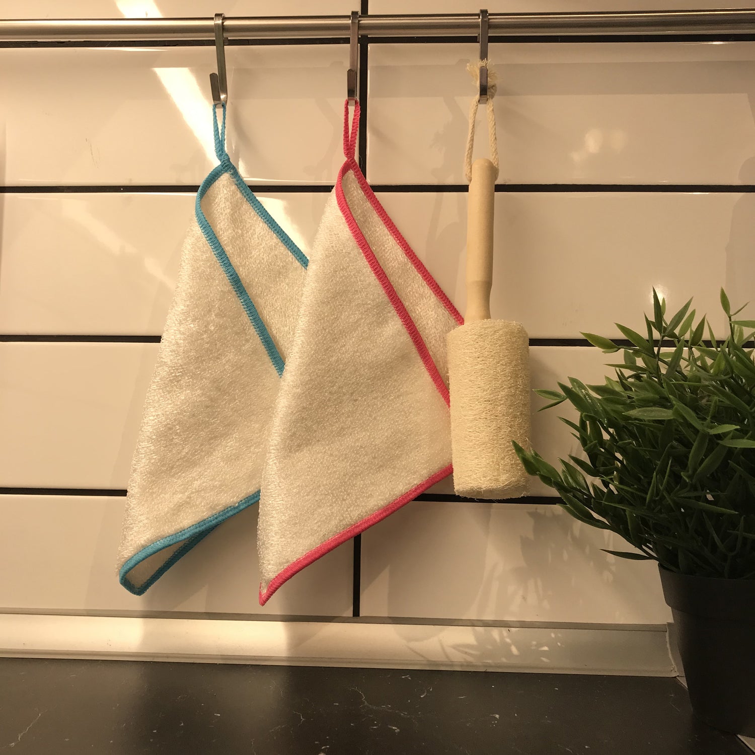 Image of reusable dishcloths - Loofah bottle brush with handle hanged on a wall in kitchen